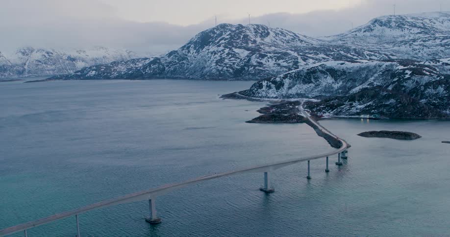 A bridge runs to the snow covered mountains