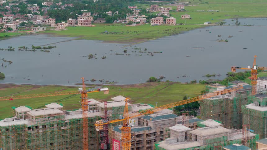 Several apartment buildings are under construction near a lake where more apartments sit on the other side