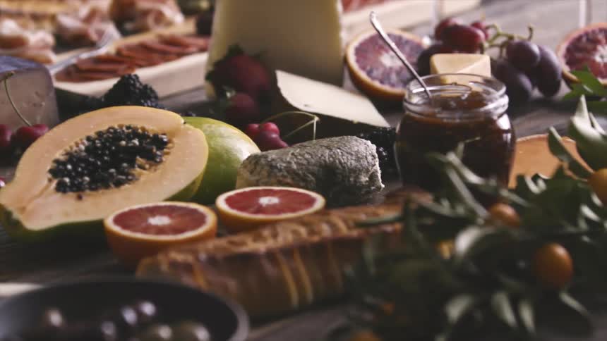 A person places blackberries on a table covered in fruit
