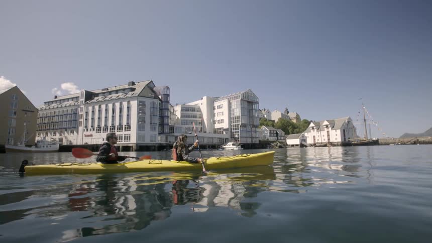 Two people are rowing a yellow boat on a sunny day