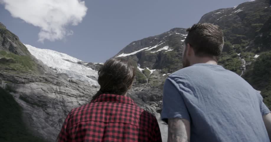Man and woman staring up at a steep mountain with remnants of snow