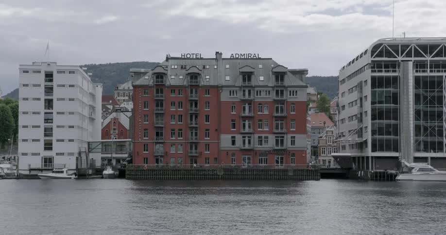 A body of water leads to some buildings by a pier