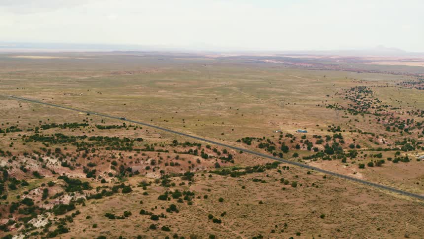 An aerial view of fields with cars driving down the road between them