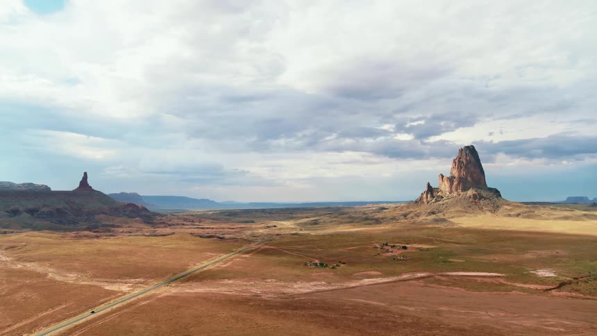 A road through a vast badland under a cloudy daytime sky
