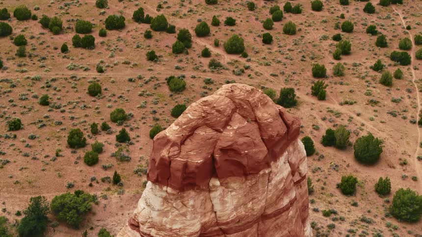An aerial view of a tall red rock formation in a desert