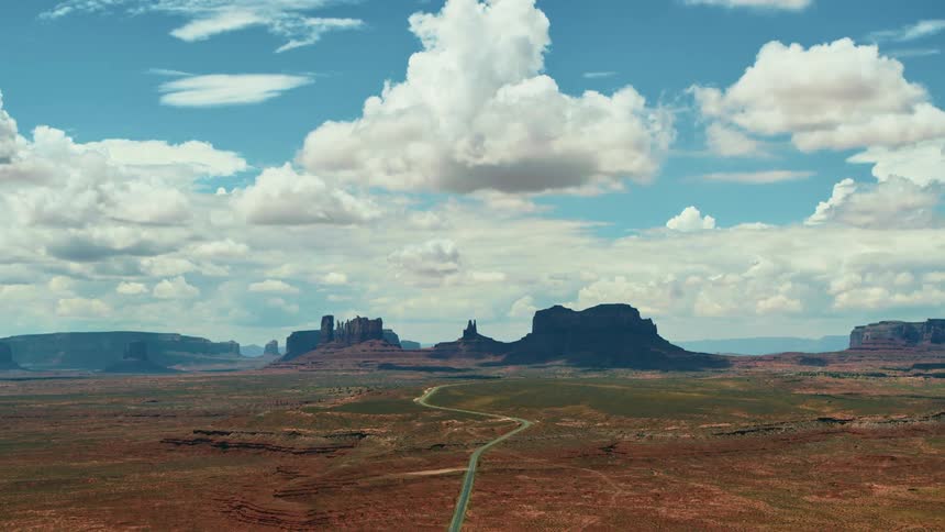 Fluffy white clouds float above large rock formations in nature