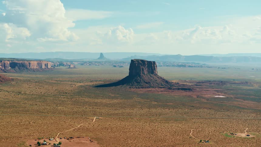 A mesa in the center of a vast shrubland on a sunny day