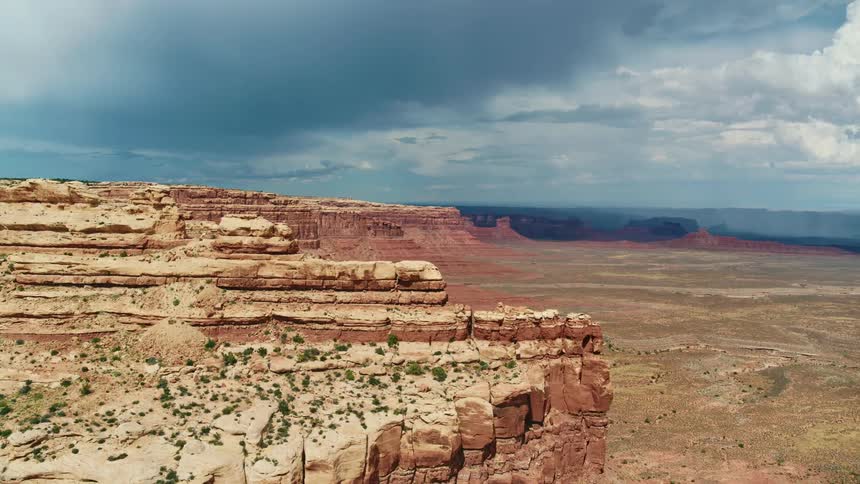 A cliff on an escarpment looming over a badland on a cloudy day