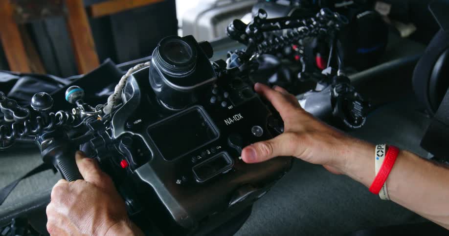 A person holds a sophisticated underwater camera and checks its readiness