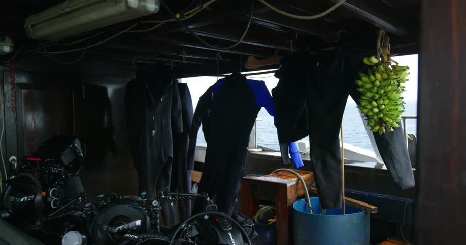 Clothing hangs from the ceiling in the inside of a boat as it travels the ocean