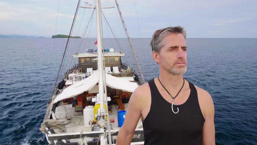 A man sailing in the ocean looks out at the water