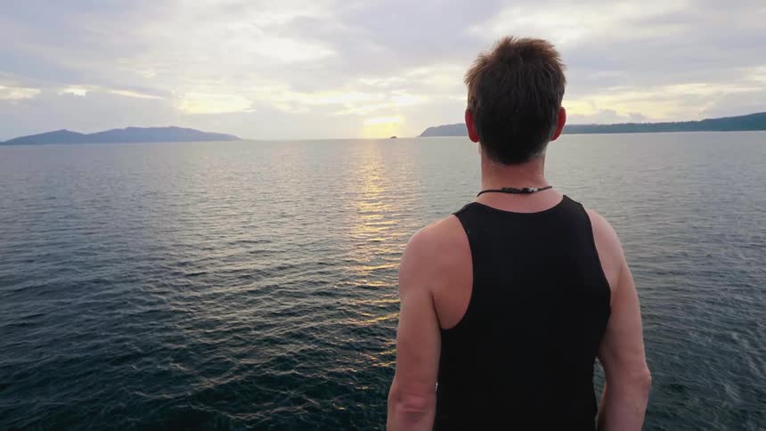 A man is looking at the ocean water