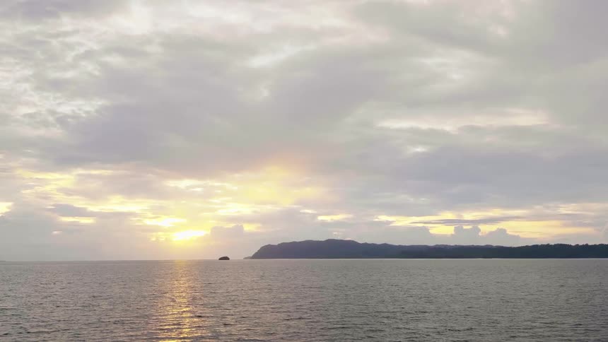 The sun is setting in the horizon above the ocean