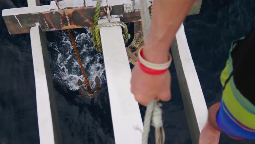 A person standing on a platform with an anchor and water below