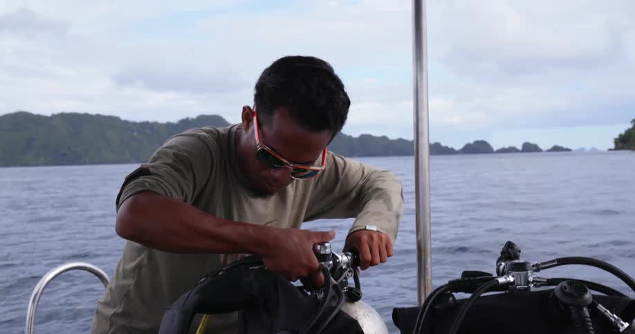 A man is preparing diving gear on the boat