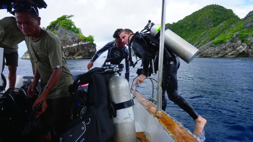 A diver climbs out of the water and back on to the tour boat that took him out