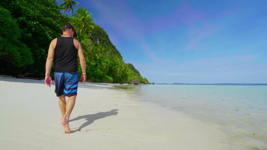 A man walking down a beach on a summer day