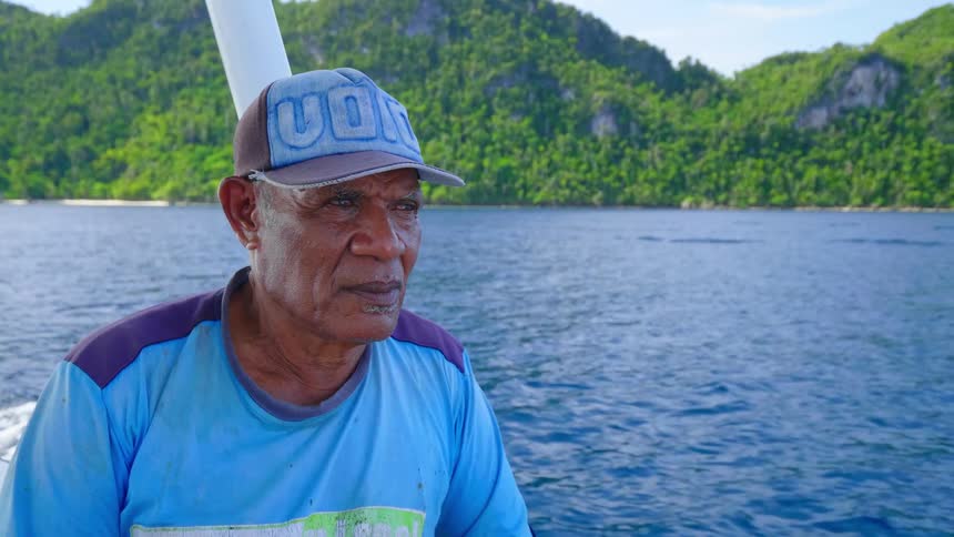 An elderly lame sitting on a moving boat on a waterway