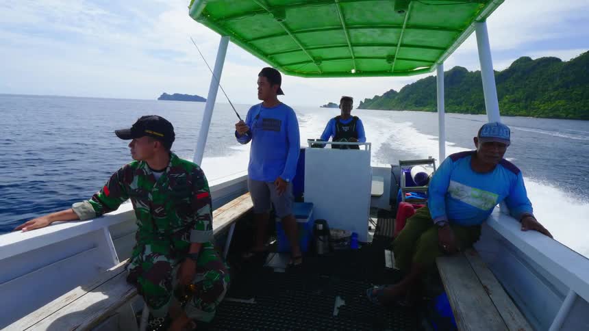 Four men sit and stand in a police patrol boat as it speeds through the water