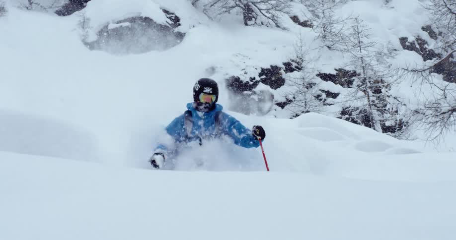 A person with a helmet and goggles skiing in a snowy forest