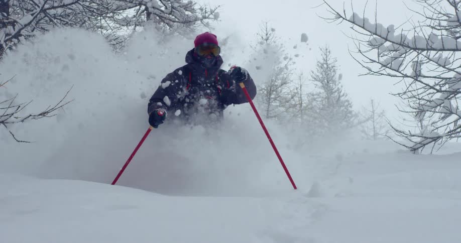 A man is skiing down a mountain in winter