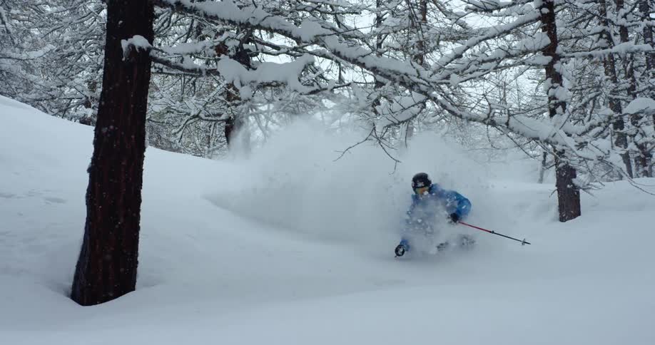 A guy is skiing down a mountain in winter