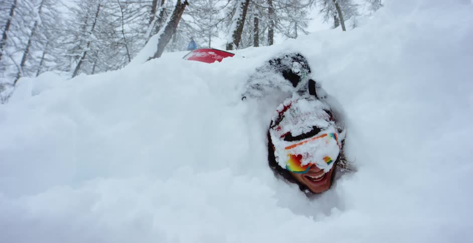 A man is smiling while covered in snow