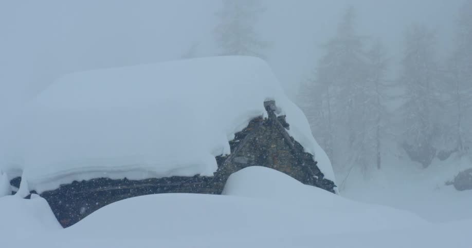 A log cabin covered in snow during a blizzard