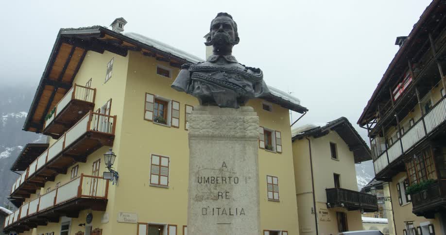 Snow falling at a statue in a small city