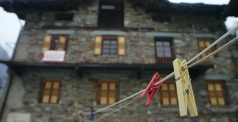 A clothesline with clothespins in the snow with a building with windows in the background