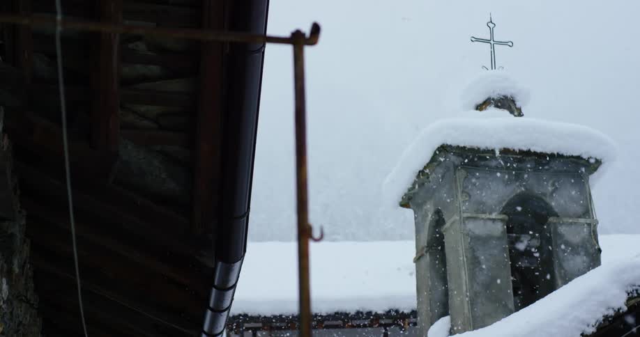 Light snow falling over the roof of a church at winter