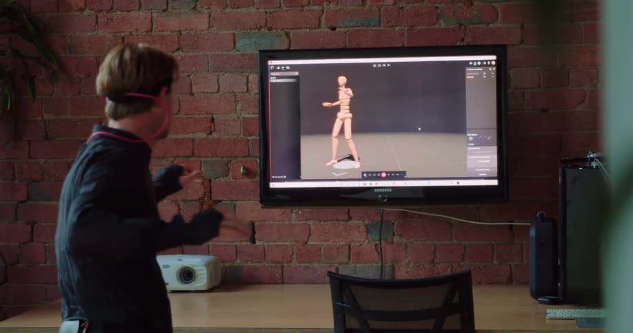 A man plays a virtual reality game and makes large movements in front of a television screen