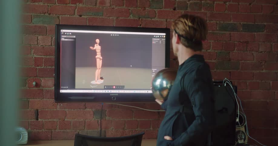 A man plays a virtual reality exercise program projected to his television and bouncing a ball in his hands