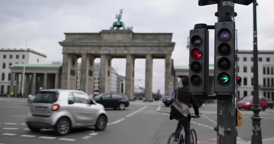 A man rides a bicycle across a busy city intersection