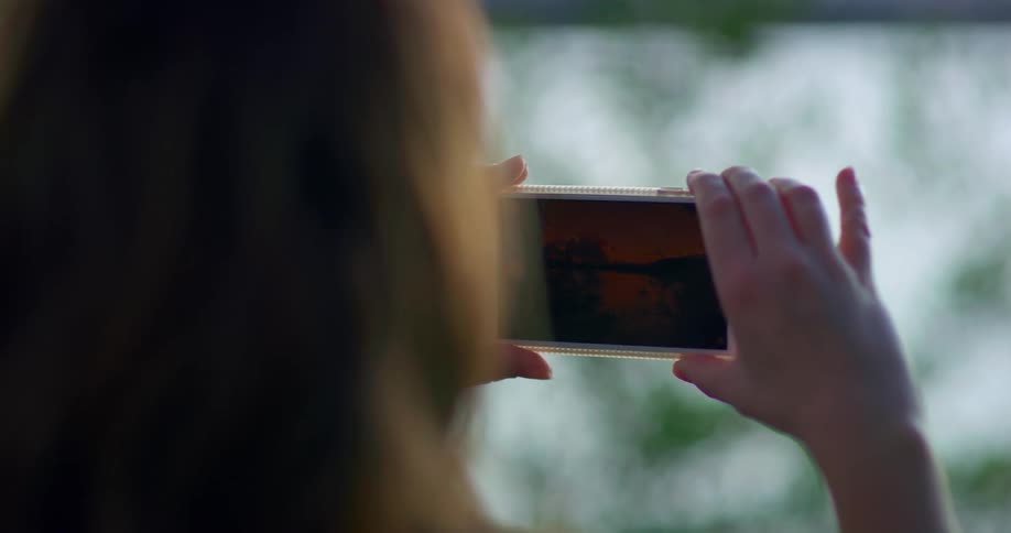 A woman is taking pictures with a cell phone