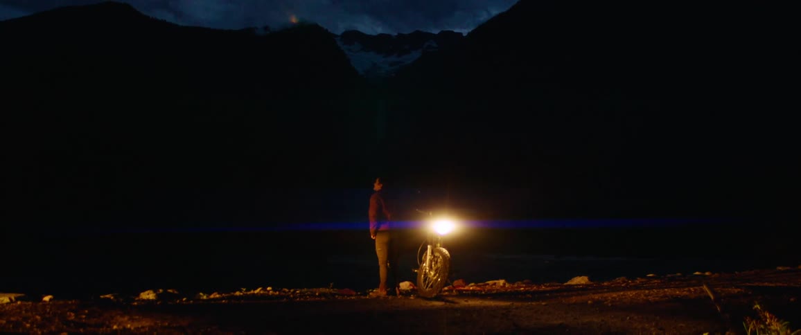 A man is standing by his motorcycle at night