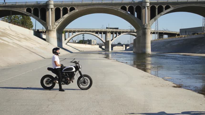 A man is sitting on a motorcycle outdoors in spring