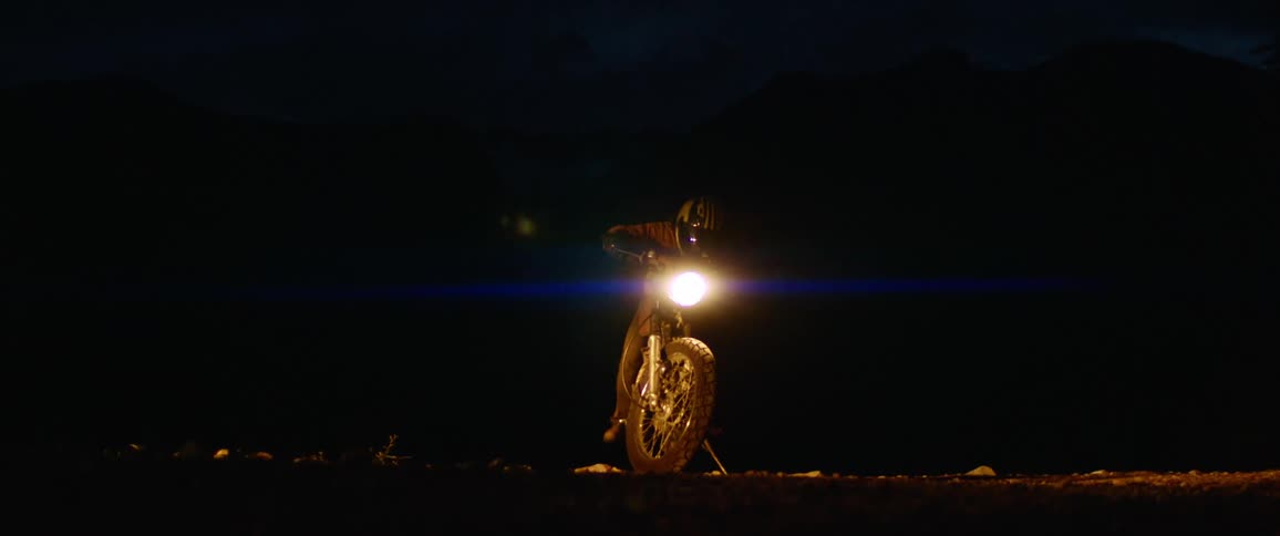 A man is riding a motorcycle outdoors at night