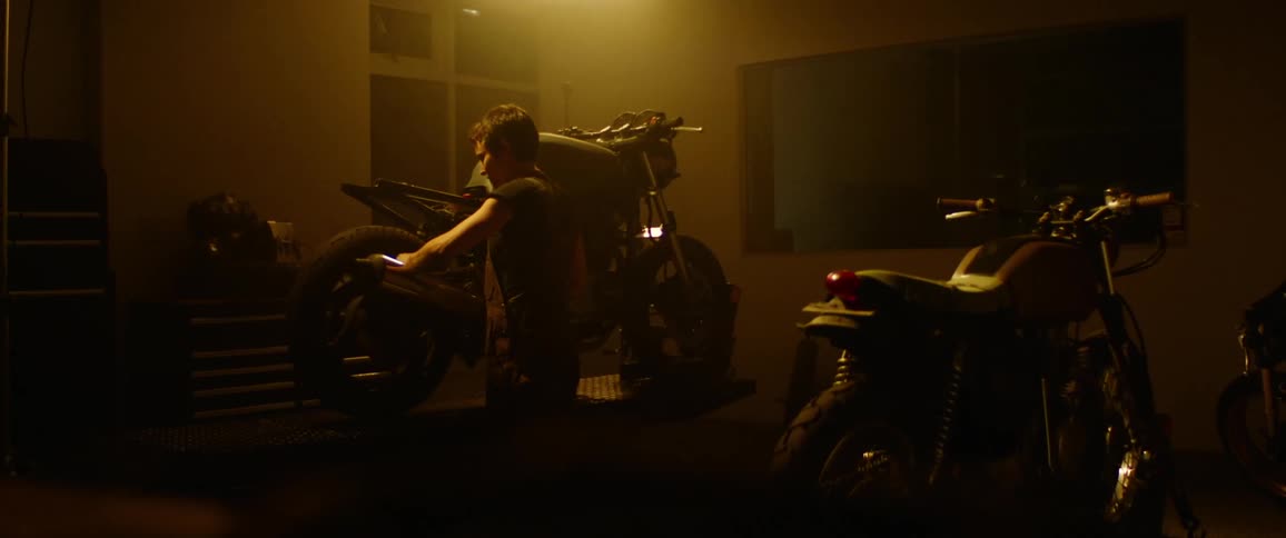 A woman is working on motorcycles in a garage at night