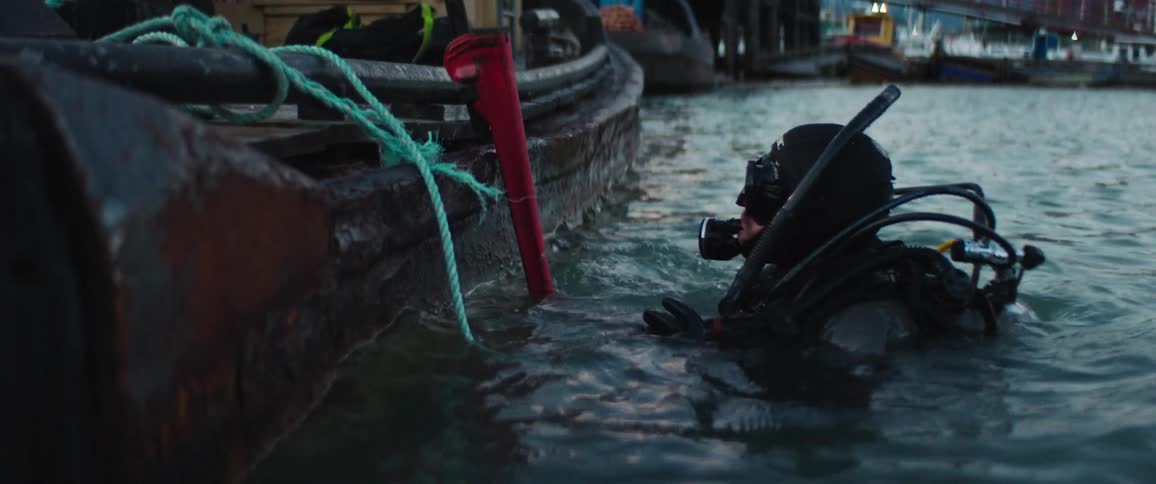 A man in scuba gear grabbing a wrench off a boat