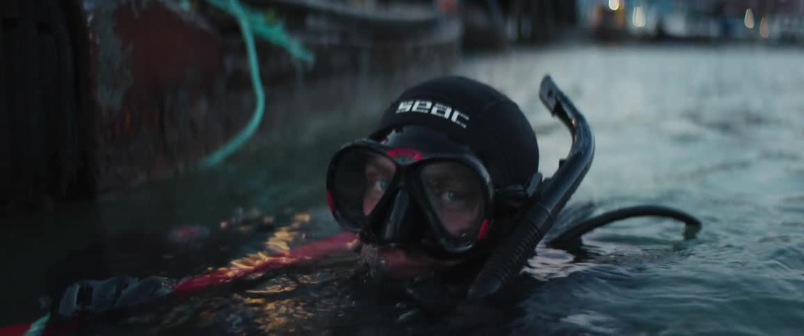 A diver is floating in the water by the pier