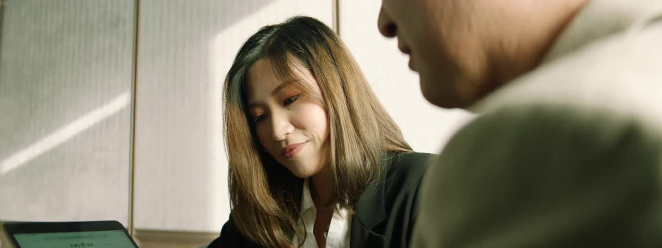 Two people look at a tablet together in the office