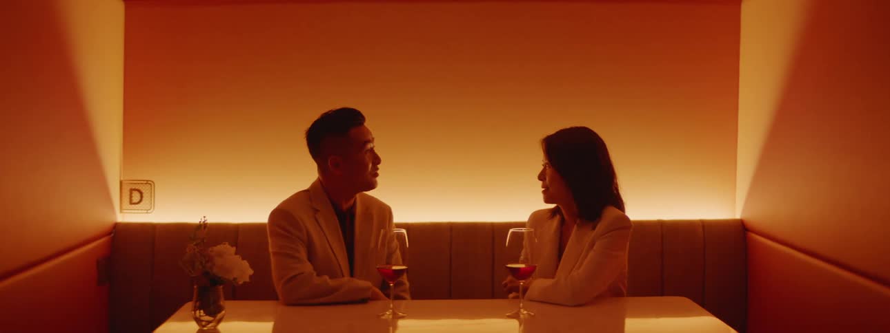 An asian couple sitting in a restaurant booth with wine