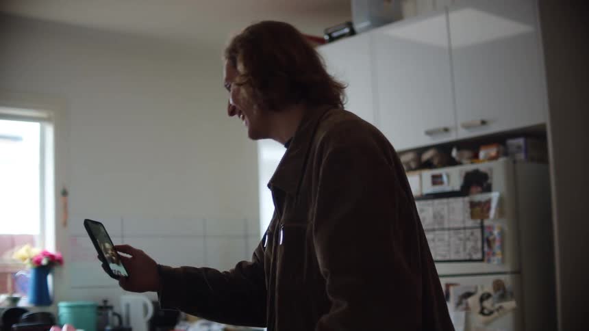 A man is laughing as he talks with video on his phone