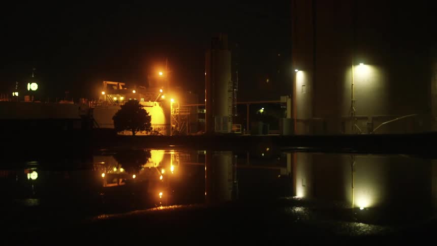 Street lamps reflected in water near buildings at night