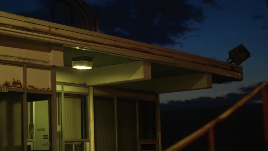 Light shines down from building overhang near windows on a cloudy night