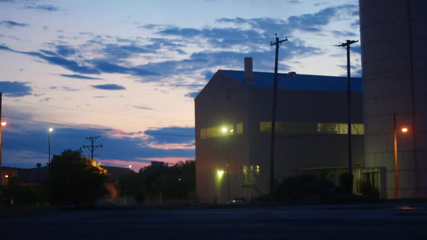 A building with utility poles and streetlights with the sky and clouds in the background