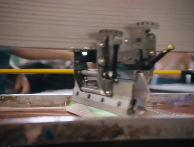 A man sprays a conveyor belt in a factory