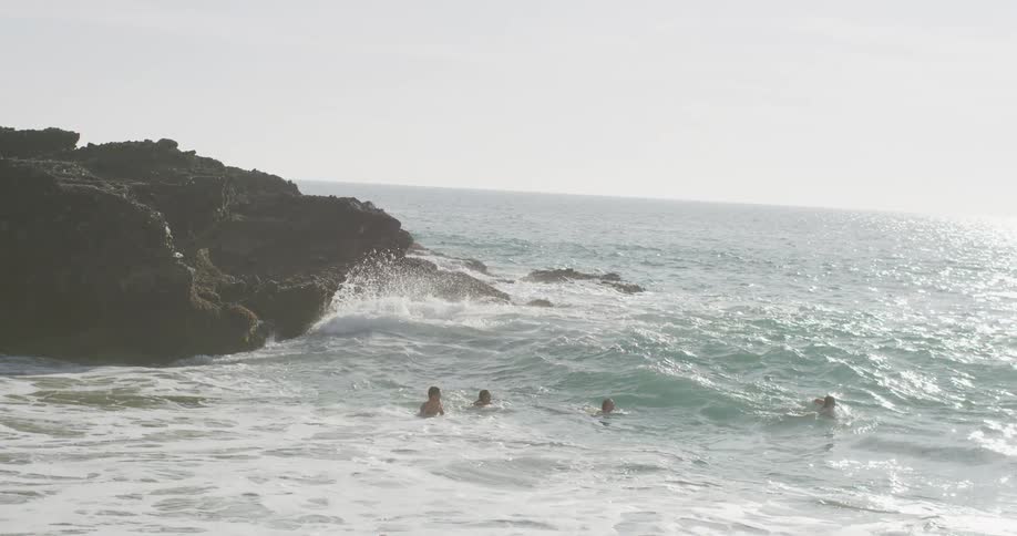 Peopleplay in ocean near shore one tumbling in crashing wave