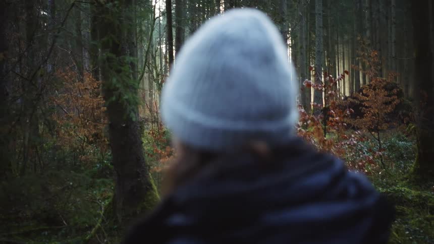 A woman is walking outdoors through a forest